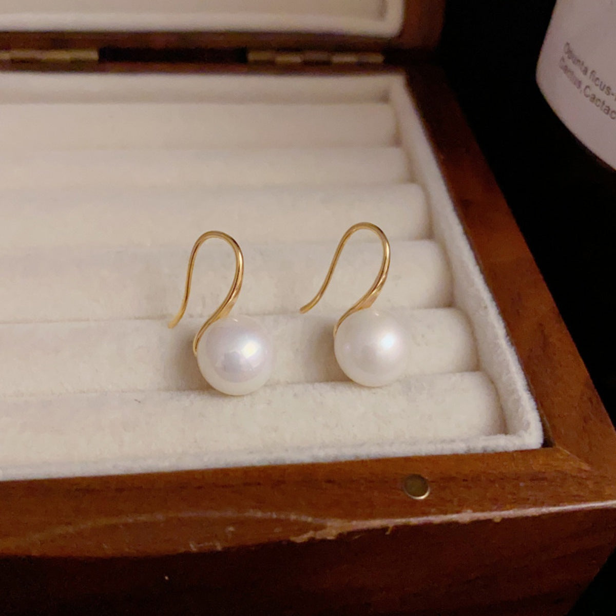 Gold drop earrings with freshwater pearls in a jewelry box.