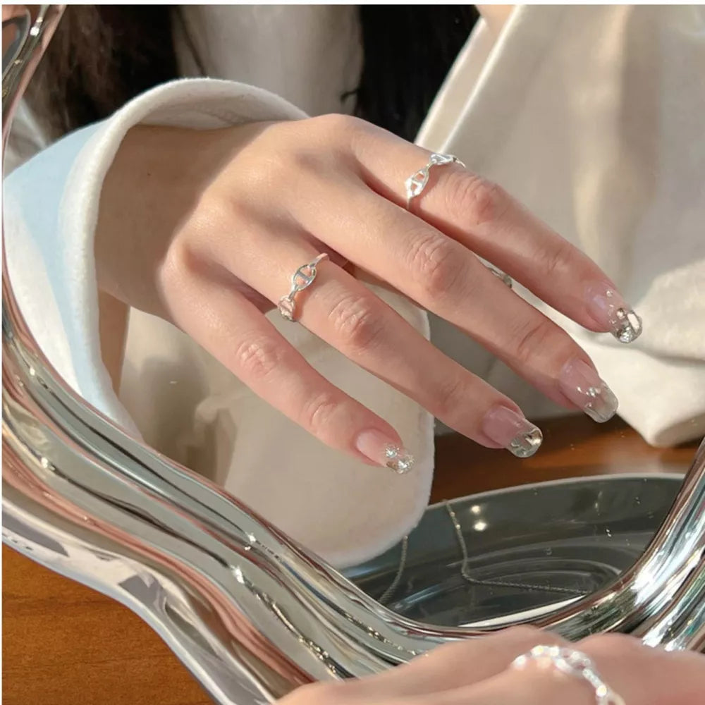 Sleek sterling silver ring with geometric chain-link design on a woman's hand.