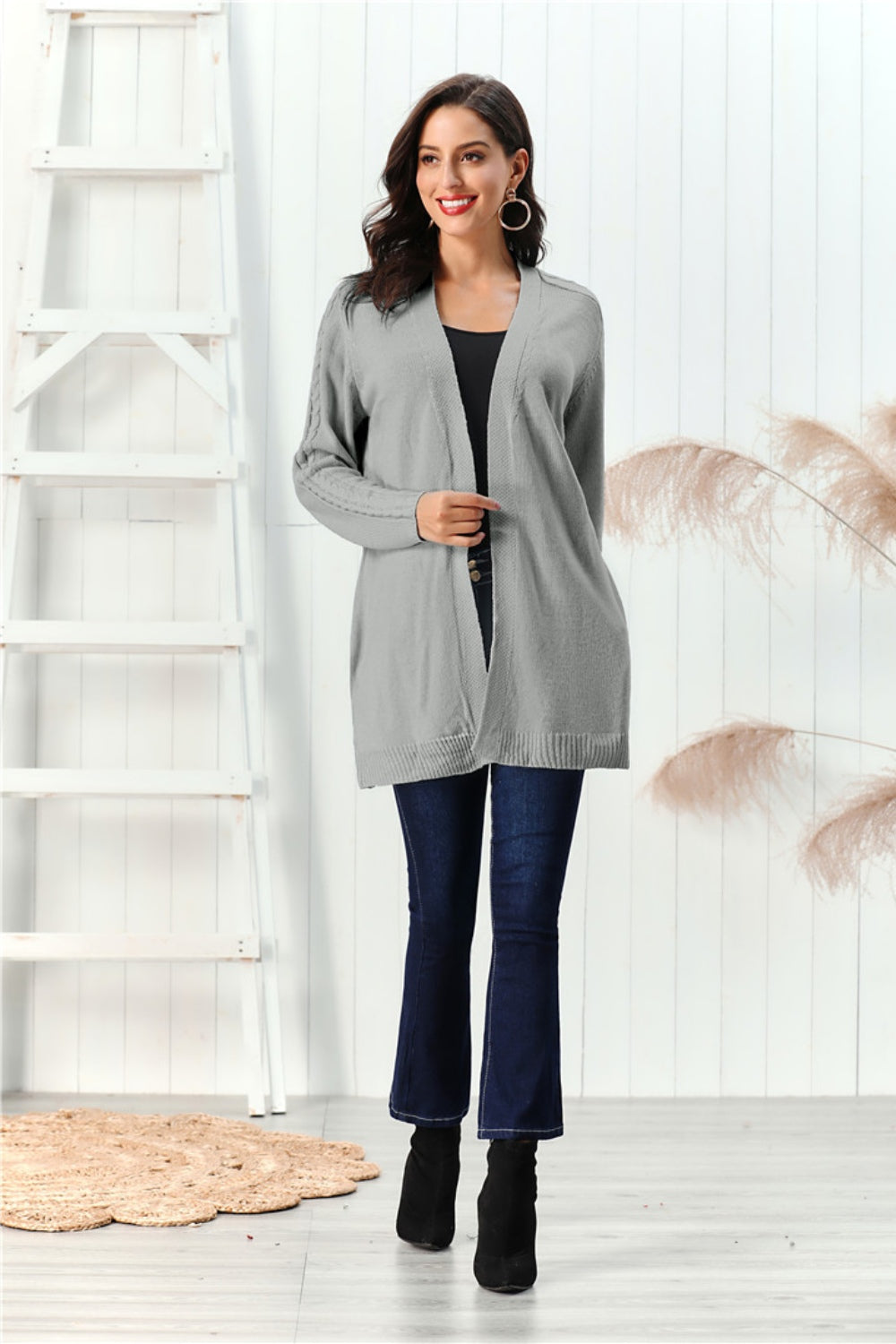 Gray cable knit open front cardigan with textured sleeves and open pockets.