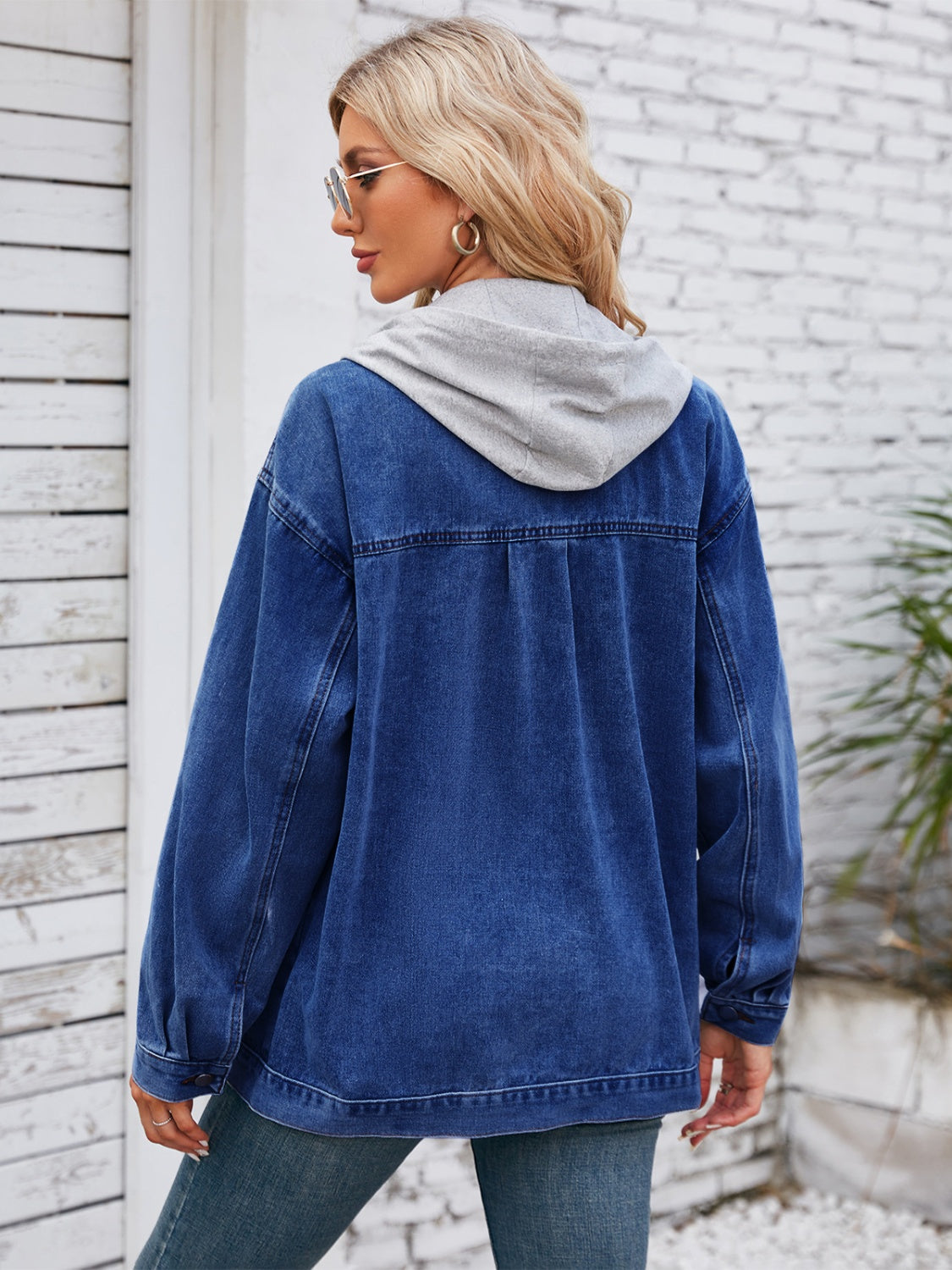 Oversized dark blue denim jacket with grey hood detail, buttoned cuffs, and casual cut.