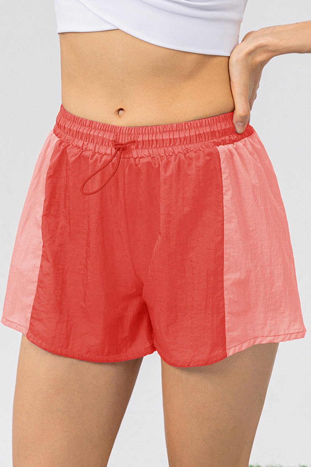 Colorblock running shorts in coral and light coral with drawstring waist.