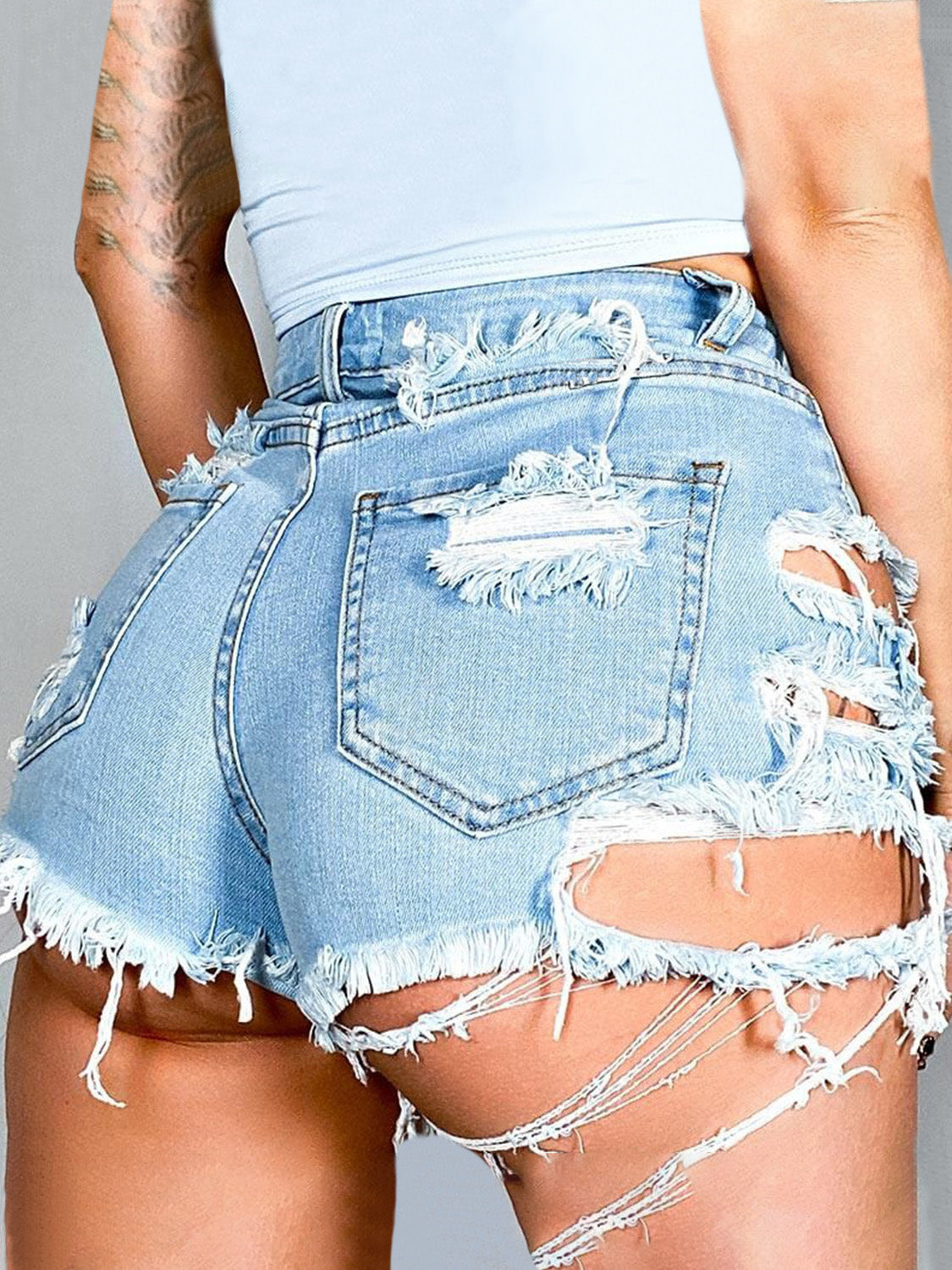 Light wash distressed denim shorts with extreme cutouts and frayed hem.