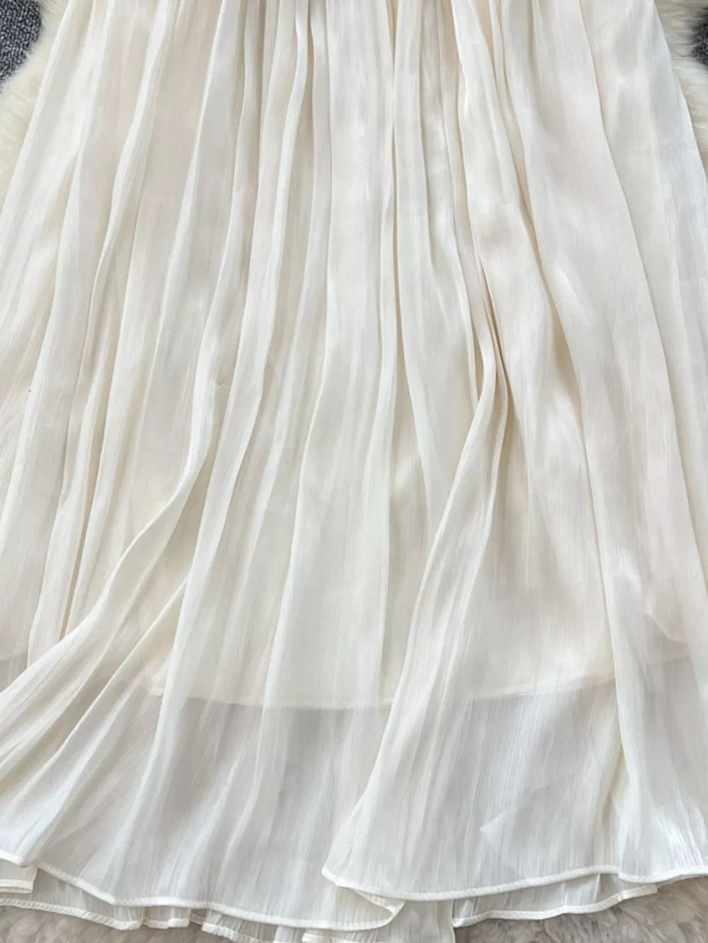 Cream pleated maxi skirt with flowing fabric and delicate pleats.