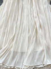 Cream pleated maxi skirt with flowing fabric and delicate pleats.