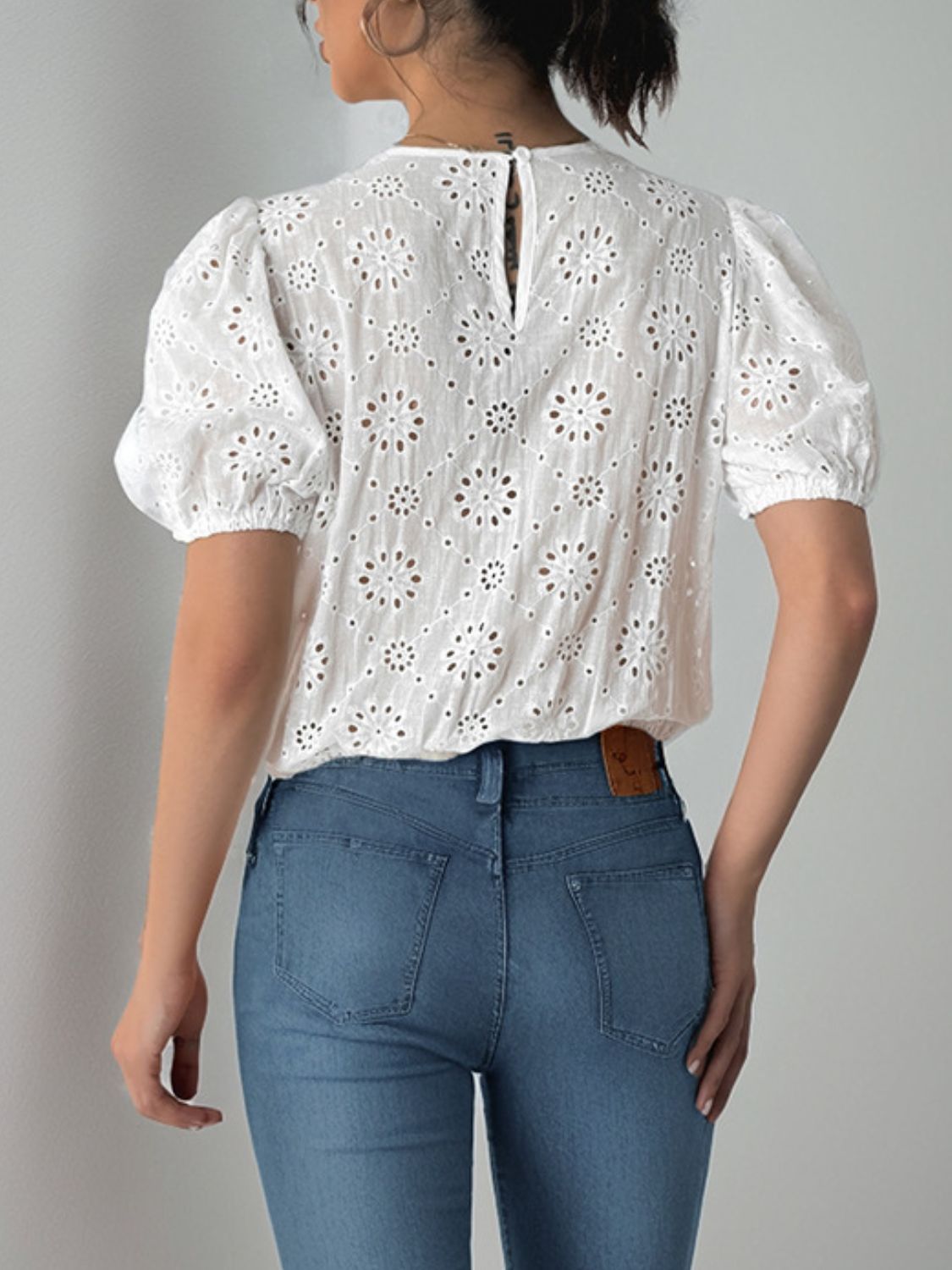 White eyelet bodysuit with puff sleeves and floral pattern, back view.