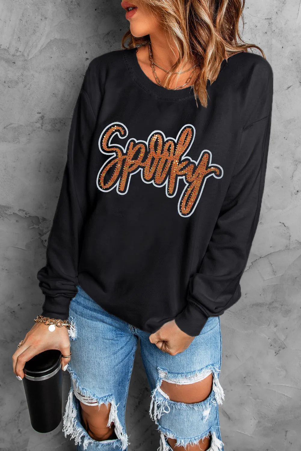 Black crewneck sweatshirt with orange glitter Spooky graphic.