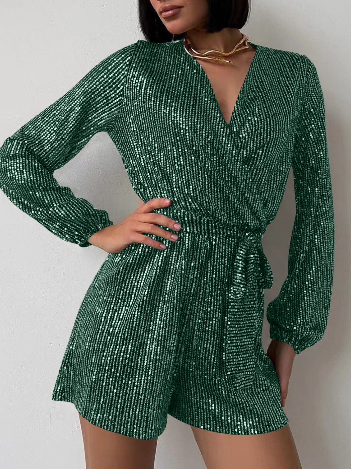 Dark green sequin wrap romper with blouson sleeves and tie waist.