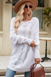 White distressed knit sweater with boat neck and long sleeves, styled with jeans and a hat.