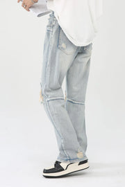 Light wash denim trousers with distressed knee slits and frayed hems.