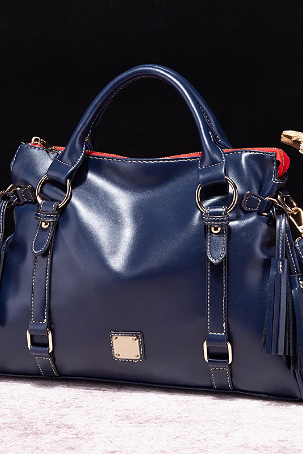 Dark blue structured satchel bag with gold hardware and tassel detail