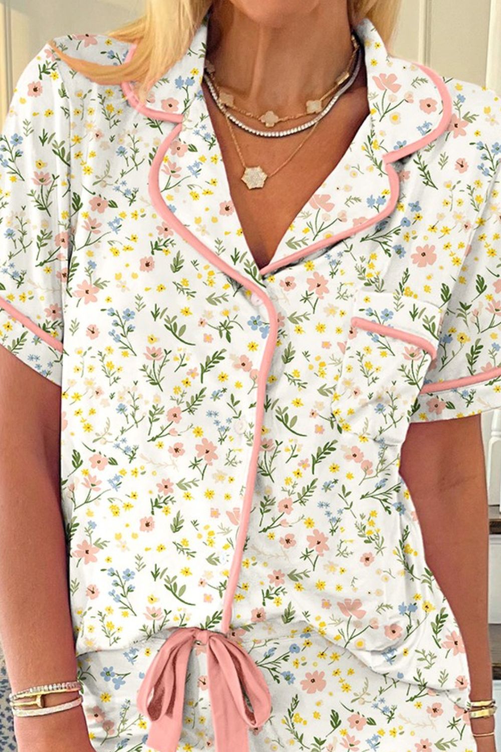 Pajama set with floral print, pink trim, button front, and bow detail.