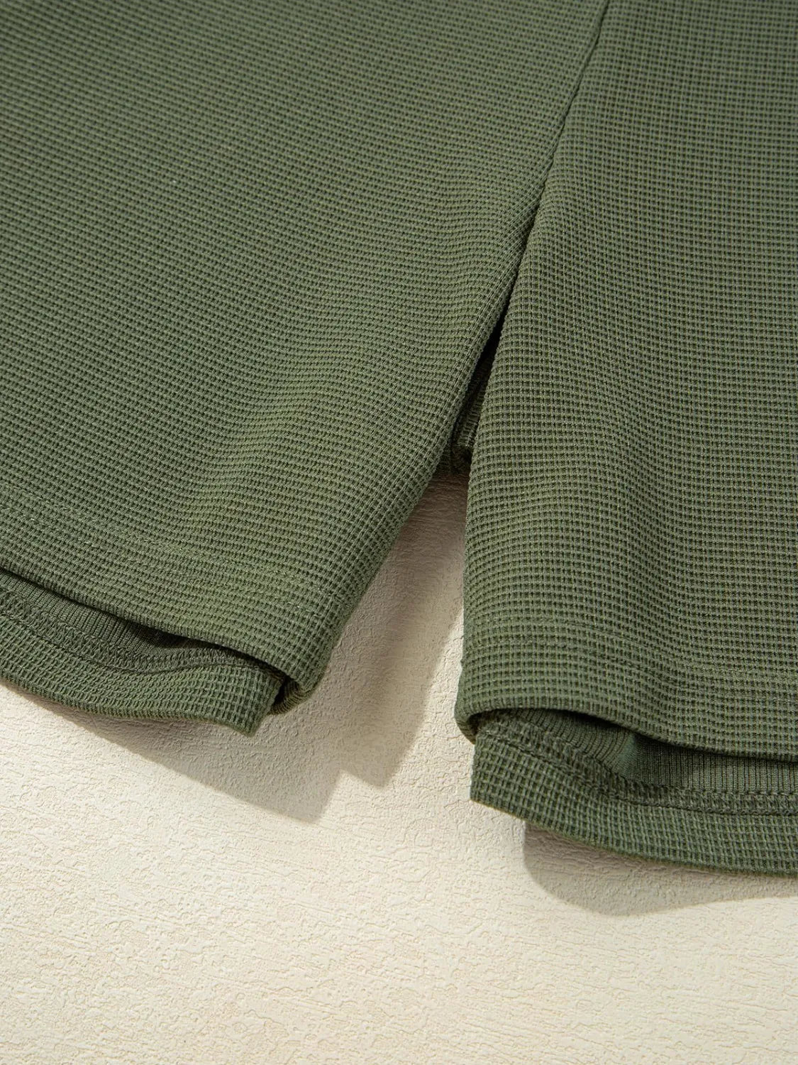 Moss green waffle knit romper detail showing hem and side slit