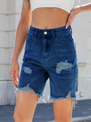 Distressed denim bermuda shorts in medium wash with frayed hem and ripped details.