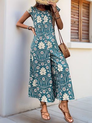 Botanical print culotte jumpsuit in dark green with short sleeves and wide legs.