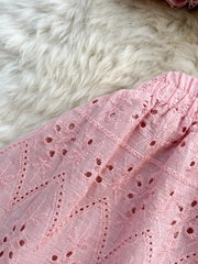 Pink eyelet maxi skirt with elastic waistband and intricate floral embroidery detail.