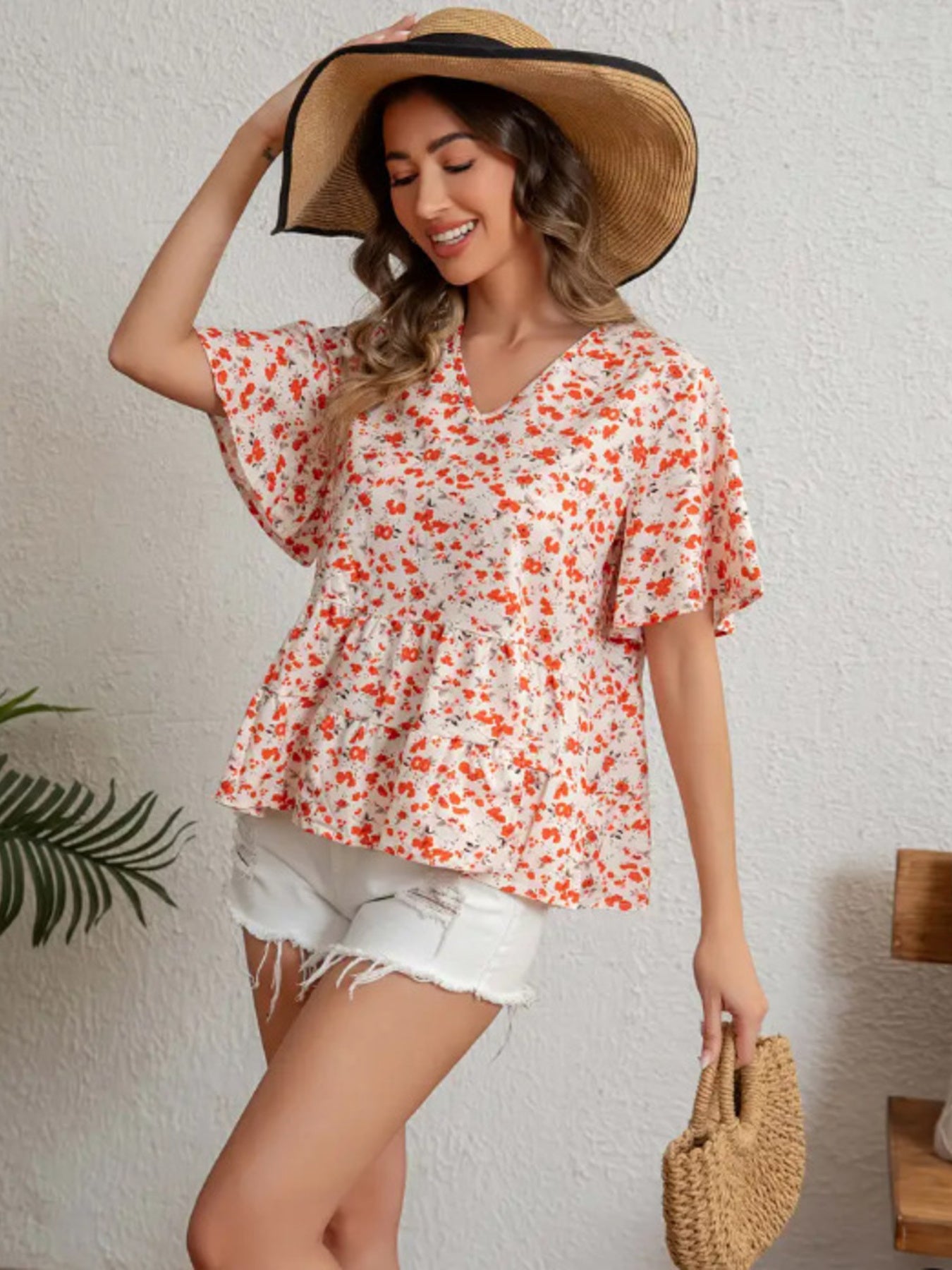 Vibrant floral peplum blouse with ruffle sleeves and V-neck.