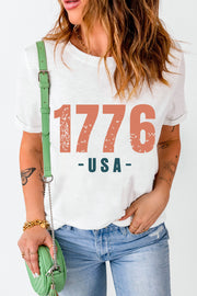 White graphic t-shirt with distressed 1776 USA print and rolled sleeves.