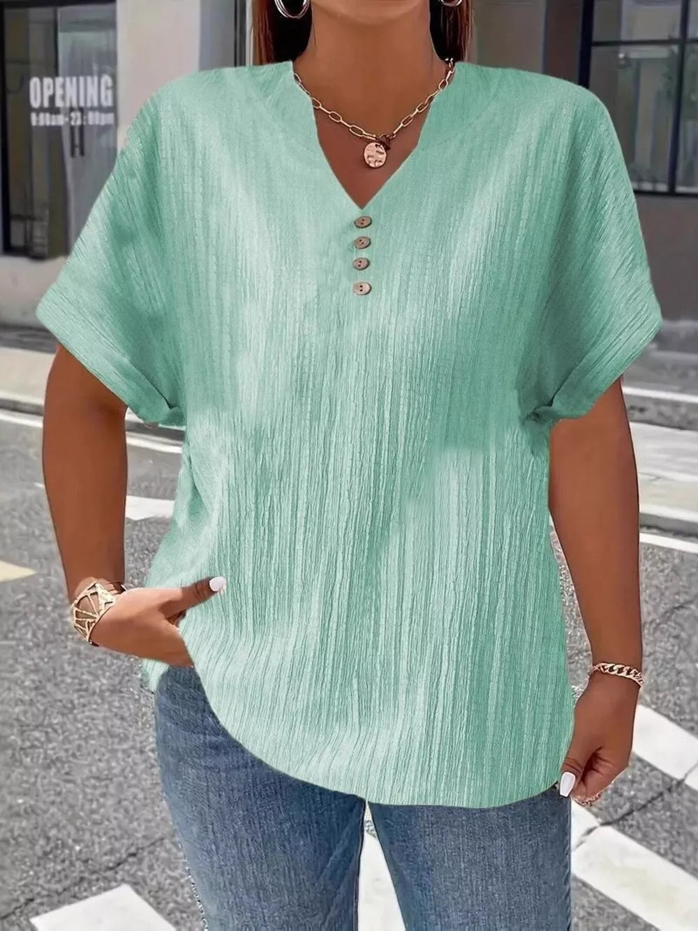 Textured light green v-neck t-shirt with decorative buttons and cuffed short sleeves.