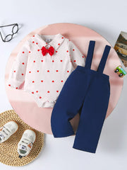 White striped baby bodysuit with red hearts and red bow tie, paired with navy suspender pants.