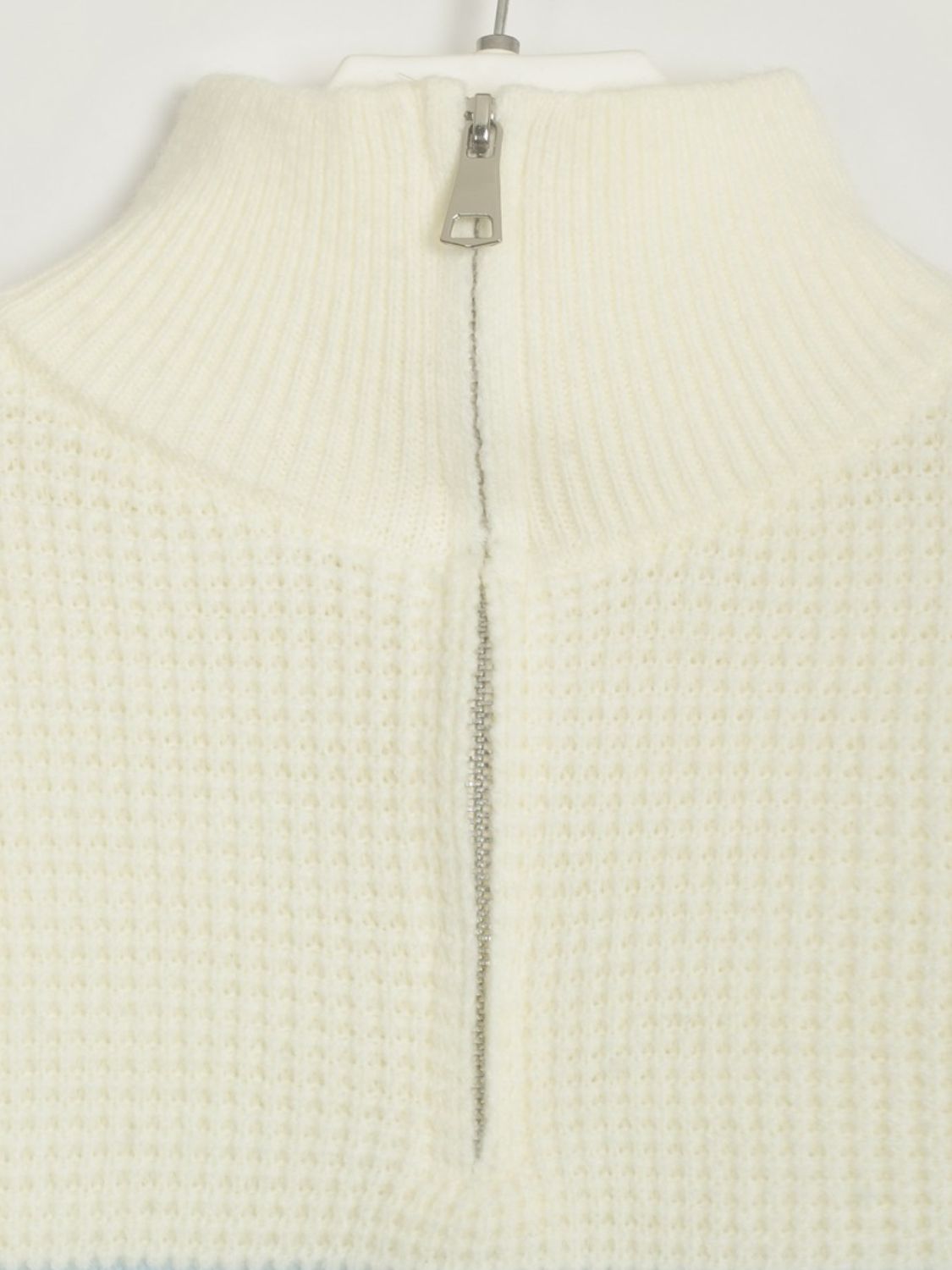 Cream ribbed knit sweater with half-zip neckline and textured waffle knit detail.