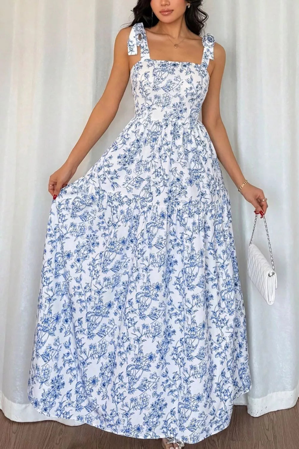 Maxi dress with blue floral print, square neck, tie straps, and tiered skirt.