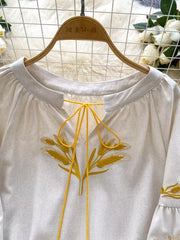 White tie-neck blouse with yellow wheat embroidery and braided ties.