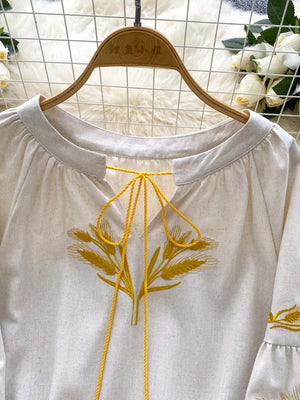 White tie-neck blouse with yellow wheat embroidery and braided ties.