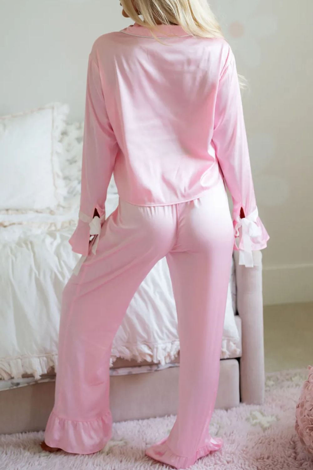 Blush pink silk pajama set with ruffle trim on collar, cuffs, and pant legs.