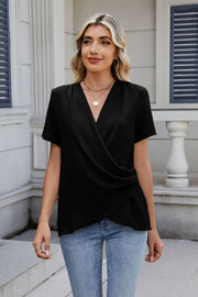 Black short sleeve blouse with draped front and V-neck, styled with jeans.