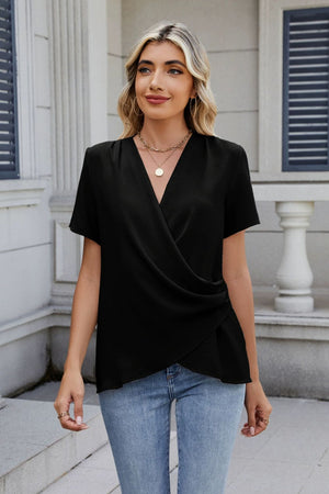 Black short sleeve blouse with draped front and V-neck, styled with jeans.