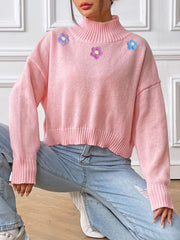 Pink cropped turtleneck sweater with embroidered flowers, ribbed cuffs and hem.