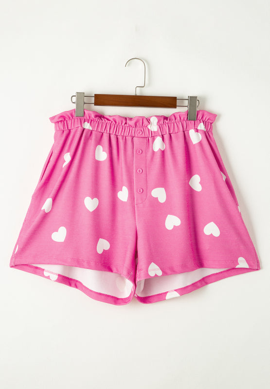Hot pink heart print pajama shorts with elastic waist and button front detail.