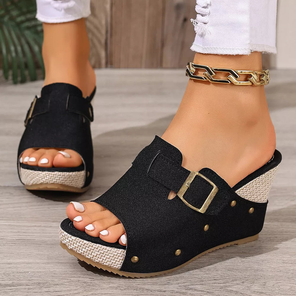 Black wedge sandals with decorative gold accents and buckle detail.