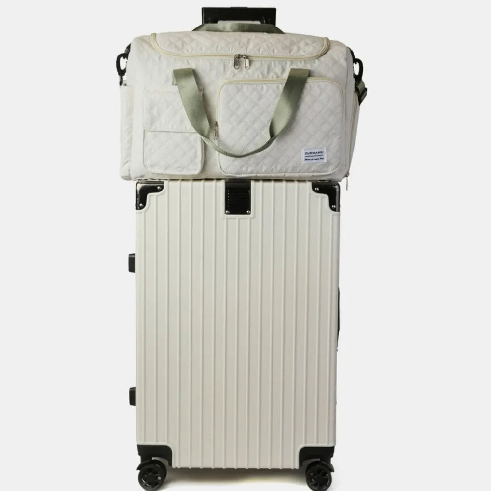 White quilted duffel bag with olive accents on top of a white ribbed suitcase.