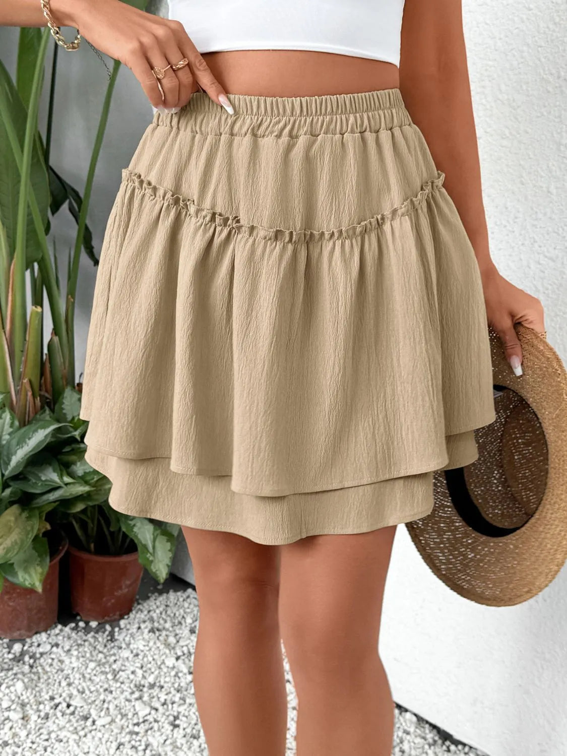 Tiered ruffle mini skirt in tan with elastic waist and textured fabric.