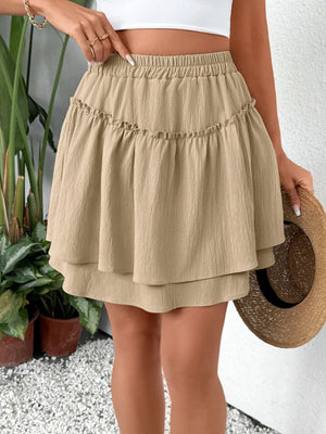 Tiered ruffle mini skirt in tan with elastic waist and textured fabric.
