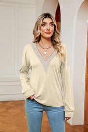 Relaxed knit sweater in pastel yellow with lace-trimmed V-neck and long sleeves.