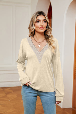 Relaxed knit sweater in pastel yellow with lace-trimmed V-neck and long sleeves.