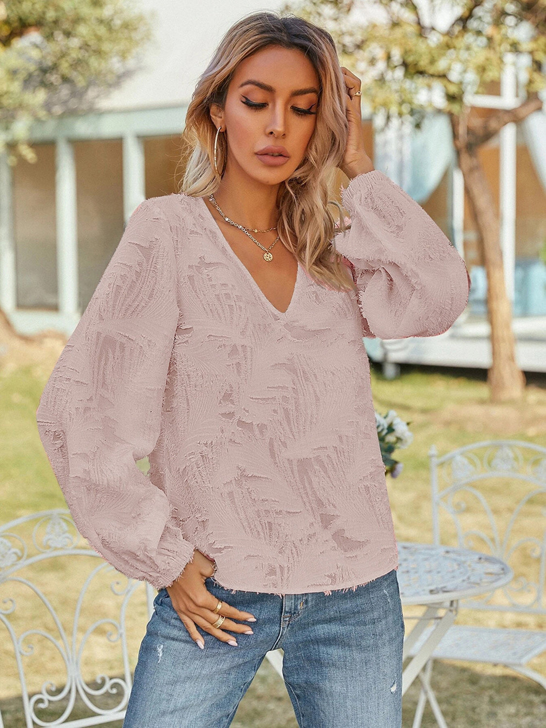 Blush pink textured puff sleeve V-neck blouse with all-over feather-like pattern.