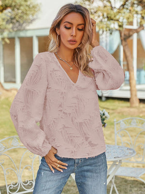 Blush pink textured puff sleeve V-neck blouse with all-over feather-like pattern.