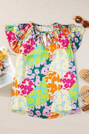 Floral patchwork ruffle sleeve blouse with tie neck and bright colors.