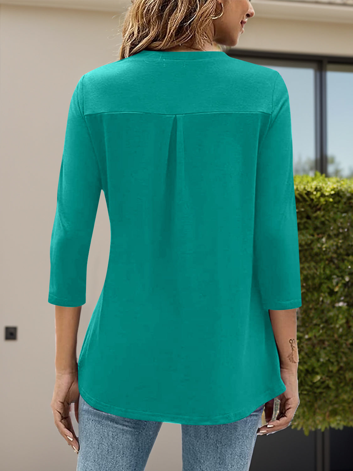 Teal three-quarter sleeve top with a V-neck and back pleat detail.
