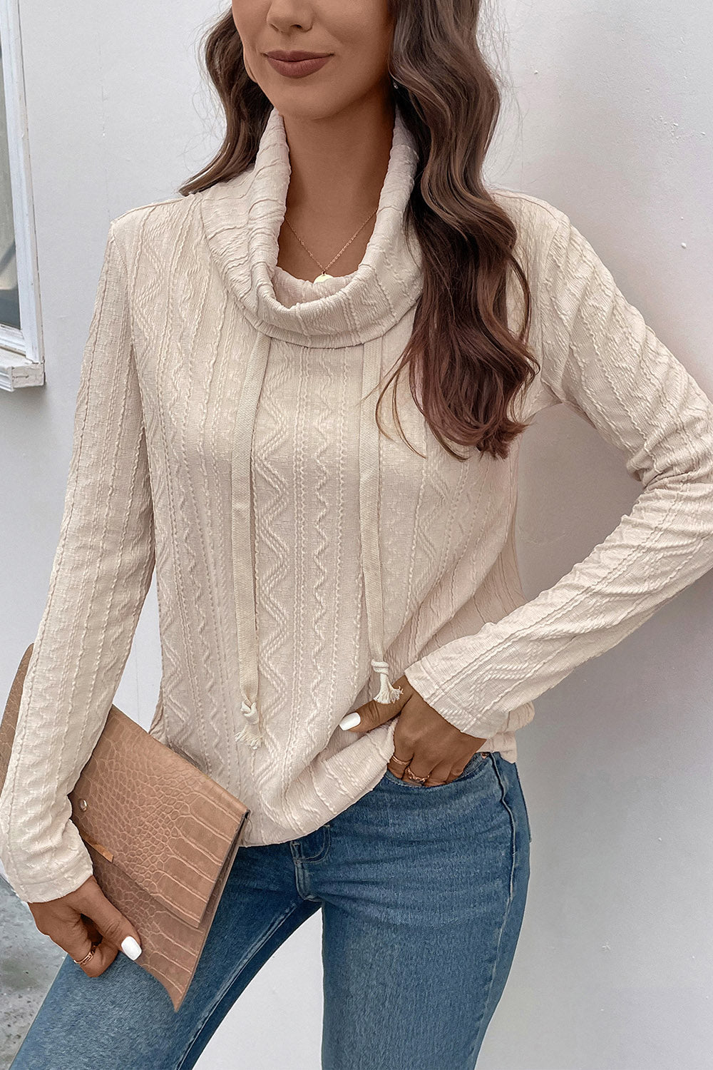 Beige textured cowl neck knit sweater with drawstring detail and long sleeves.