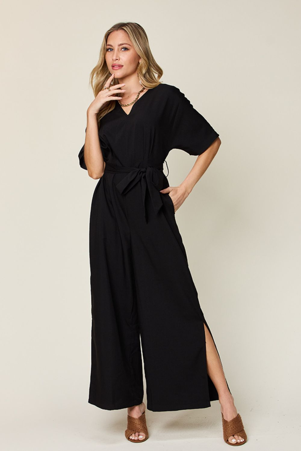 Black wrap jumpsuit with V-neck, short sleeves, tie waist, and slit legs.