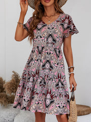 Paisley print mini dress with flutter sleeves and tiered skirt in pink, black, and cream.