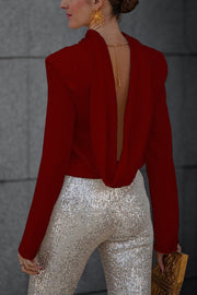 Burgundy silk blouse with a draped open back and long sleeves, styled with sequin pants.