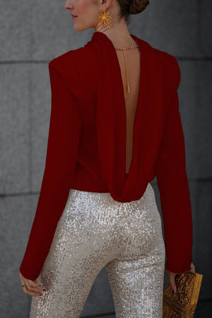 Burgundy silk blouse with a draped open back and long sleeves, styled with sequin pants.