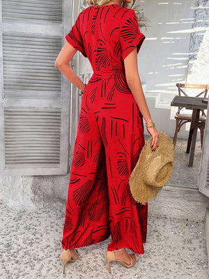 Red geometric print wide-leg jumpsuit with short sleeves and a belted waist.
