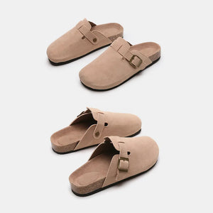 Beige suede clog slides with adjustable buckle and cork sole.