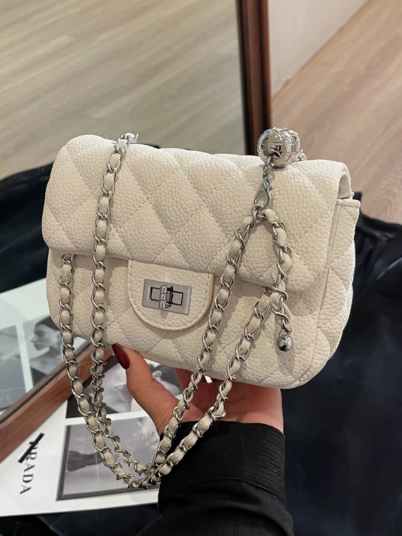 Quilted chain crossbody clutch in Rice White with silver hardware and a decorative ball charm.